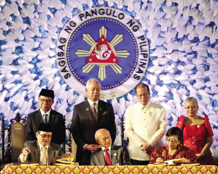 COMPREHENSIVE AGREEMENT   President Aquino and Malaysian Prime Minister Najib Abdul Razak witnessed the signing of the Comprehensive Agreement on the Bangsamoro between the Philippine government represented by chief negotiator Miriam Coronel Ferrer (seated right) and the Moro Islamic Liberation Front (MILF) represented by its peace panel chair Mohagher Iqbal (seated left) on March 27, 2014. Also in photo are Presidential Adviser on the Peace Process Teresita Quintos-Deles (right), MILF Chair Murad Ibrahim (left) and Abdul Ghafar Tenku Mohamed. LYN RILLON