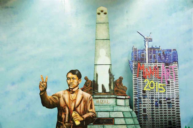 THE HERO AND THE CONDO  Jose Rizal steps down from his monument at Luneta Park in Manila in Bonifacio Juan’s installation at ManilArt 2015. ManilArt organizers invited fairgoers to have their photos taken with Rizal as spoiler, much like the Torre de Manila condominium building in the background.       MANILA.COCONUTS.COM