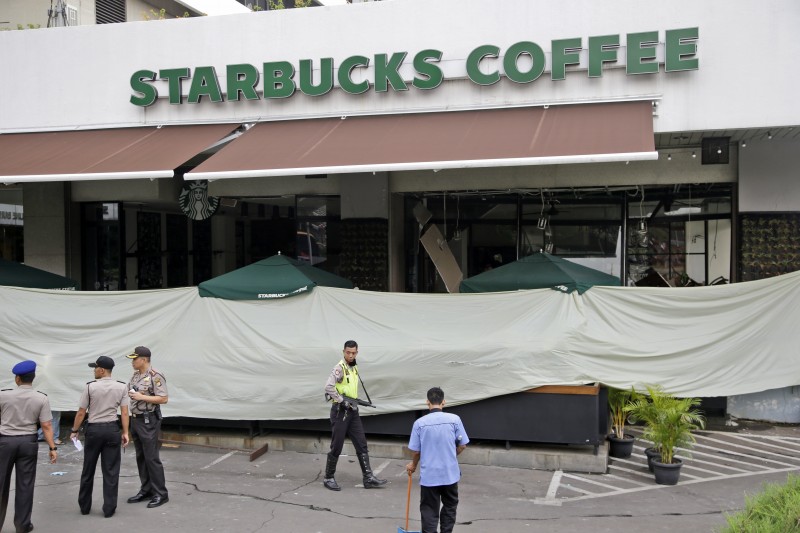 Police and officials gather in the parking lot outside the damaged Starbucks cafe where Thursday's attack occurred in Jakarta, Indonesia, on Friday, Jan. 15, 2016. A day after attackers detonated bombs and engaged in gunbattles with police in the central part of Indonesias capital, Jakarta tried to get itself back on track. (AP Photo/Tatan Syuflana)