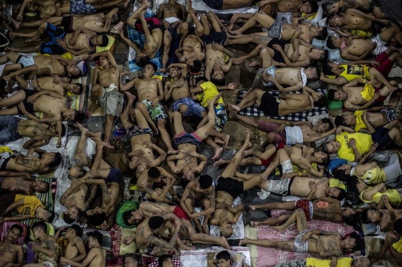 In this photo taken on July 19, 2016 inmates sleep on the ground of an open basketball court inside the Quezon City jail at night in Manila. There are 3,800 inmates at the jail, which was built six decades ago to house 800, and they engage in a relentless contest for space. Men take turns to sleep on the cracked cement floor of an open-air basketball court, the steps of staircases, underneath beds and hammocks made out of old blankets. AFP PHOTO / NOEL CELIS